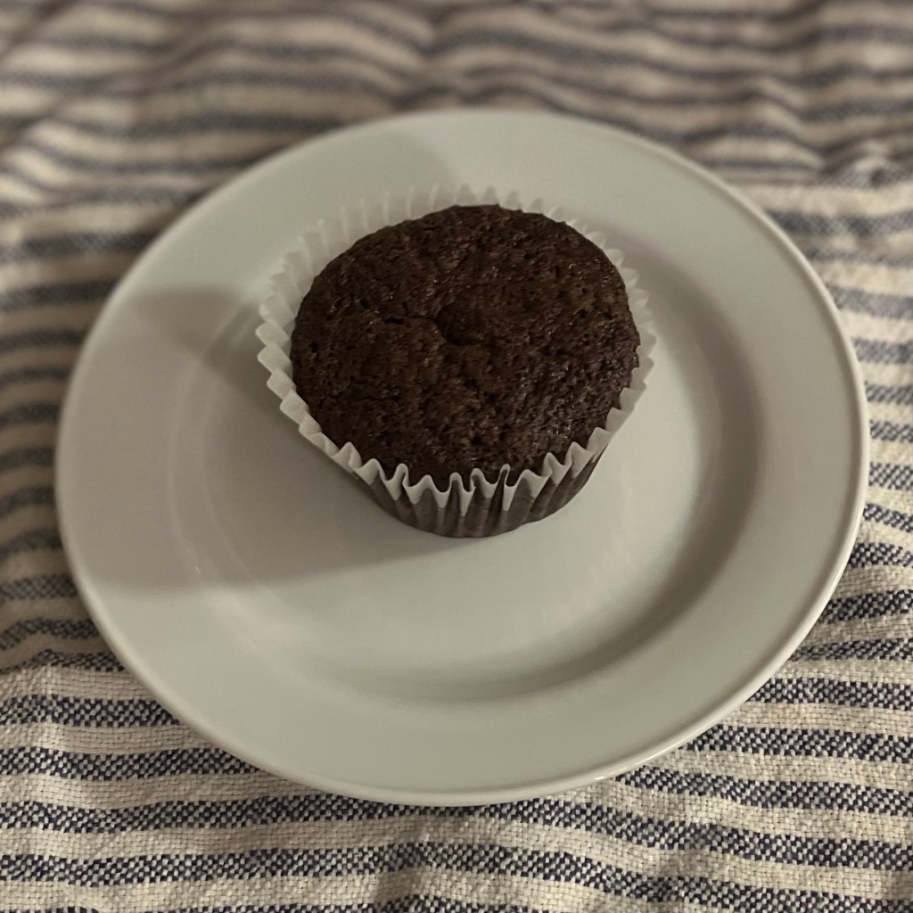 A chocolate zucchini muffin on a white plate